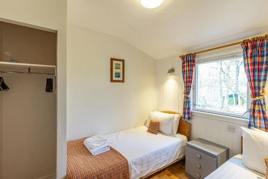 a small bedroom with two beds and a window at Heather Lodge 12 with Hot Tub in Belladrum