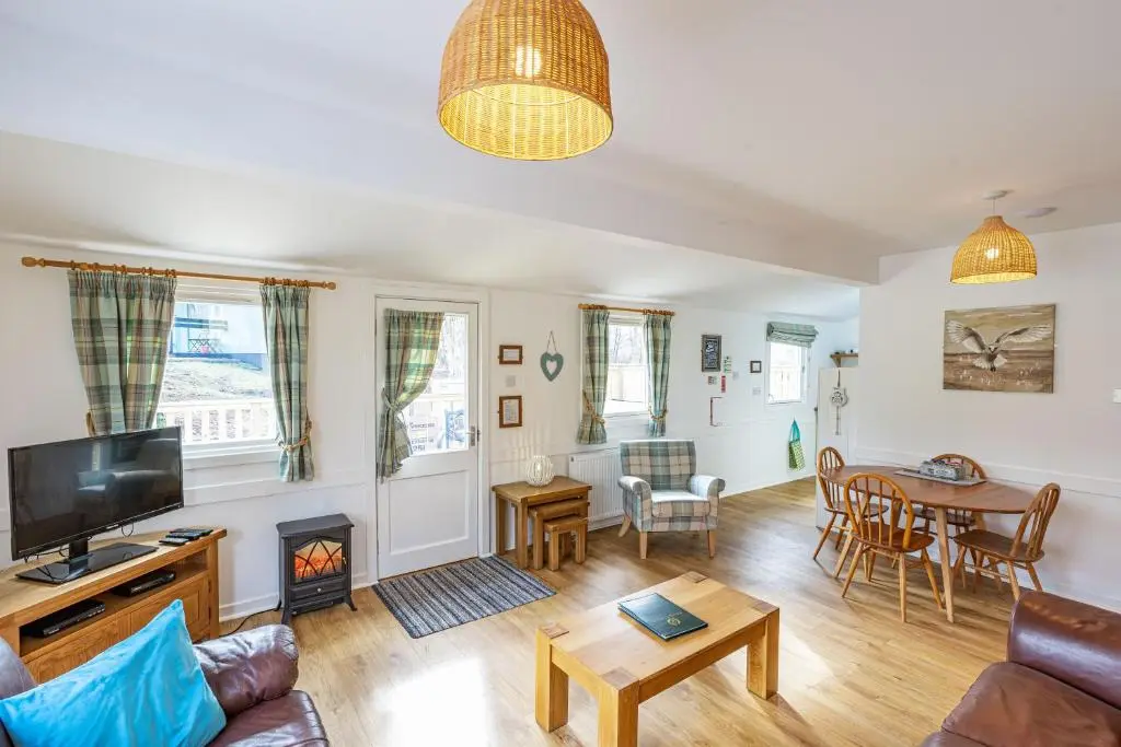 a living room with a couch and a fireplace at Heather Lodge 12 with Hot Tub in Belladrum