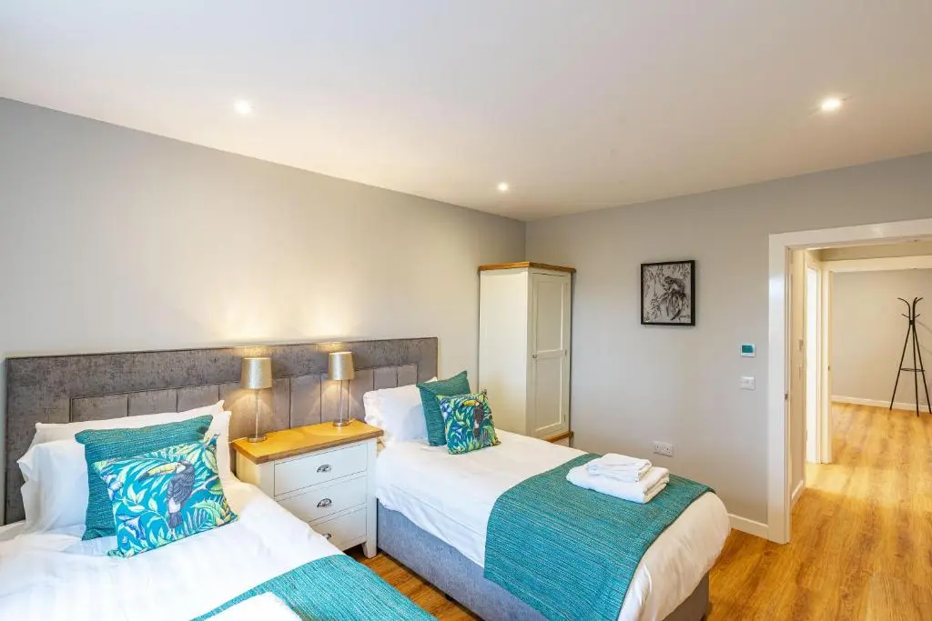 a bedroom with two beds with blue pillows at Monarch Lodge 13 with Hot Tub in Belladrum
