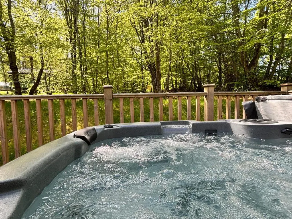a hot tub with water in it next to a fence at Monarch Lodge 13 with Hot Tub in Belladrum
