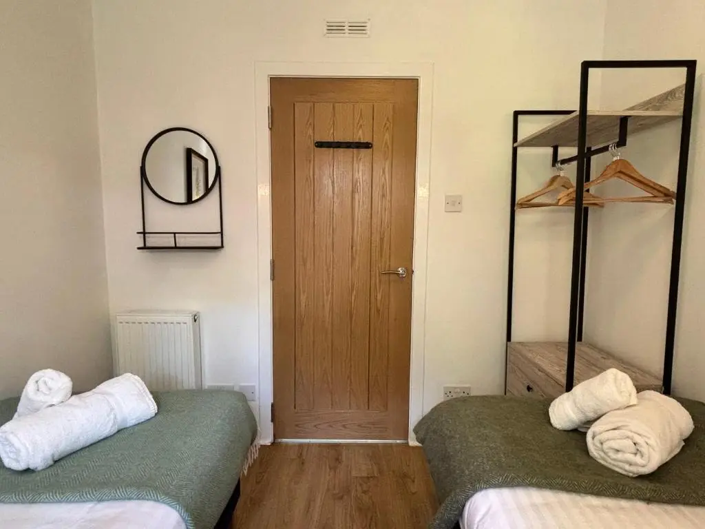 a room with two beds and a door with a mirror at Fern Lodge 11 with Hot Tub in Belladrum