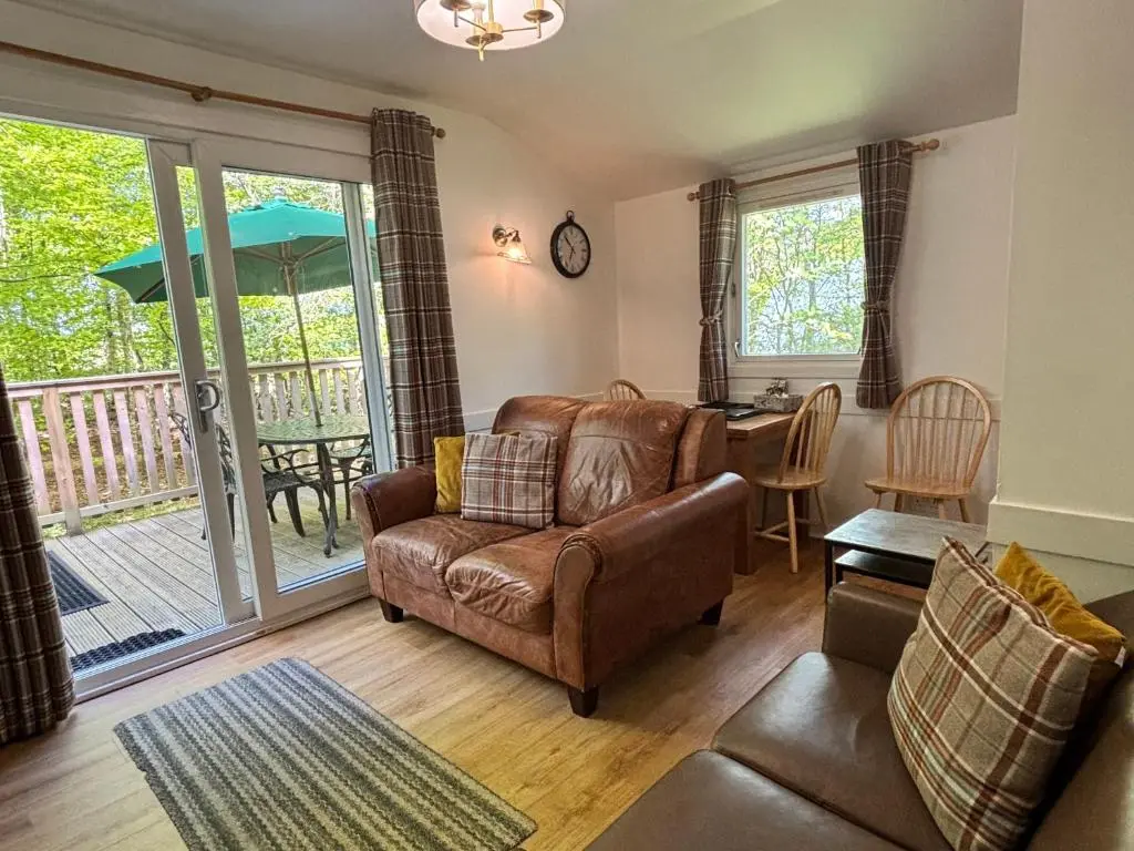 a living room with a couch and a chair and a table at Fern Lodge 11 with Hot Tub in Belladrum
