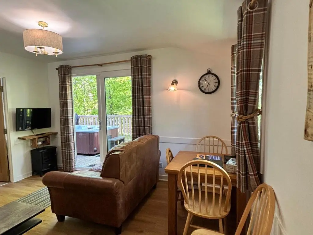 a living room with a couch and a table at Fern Lodge 11 with Hot Tub in Belladrum