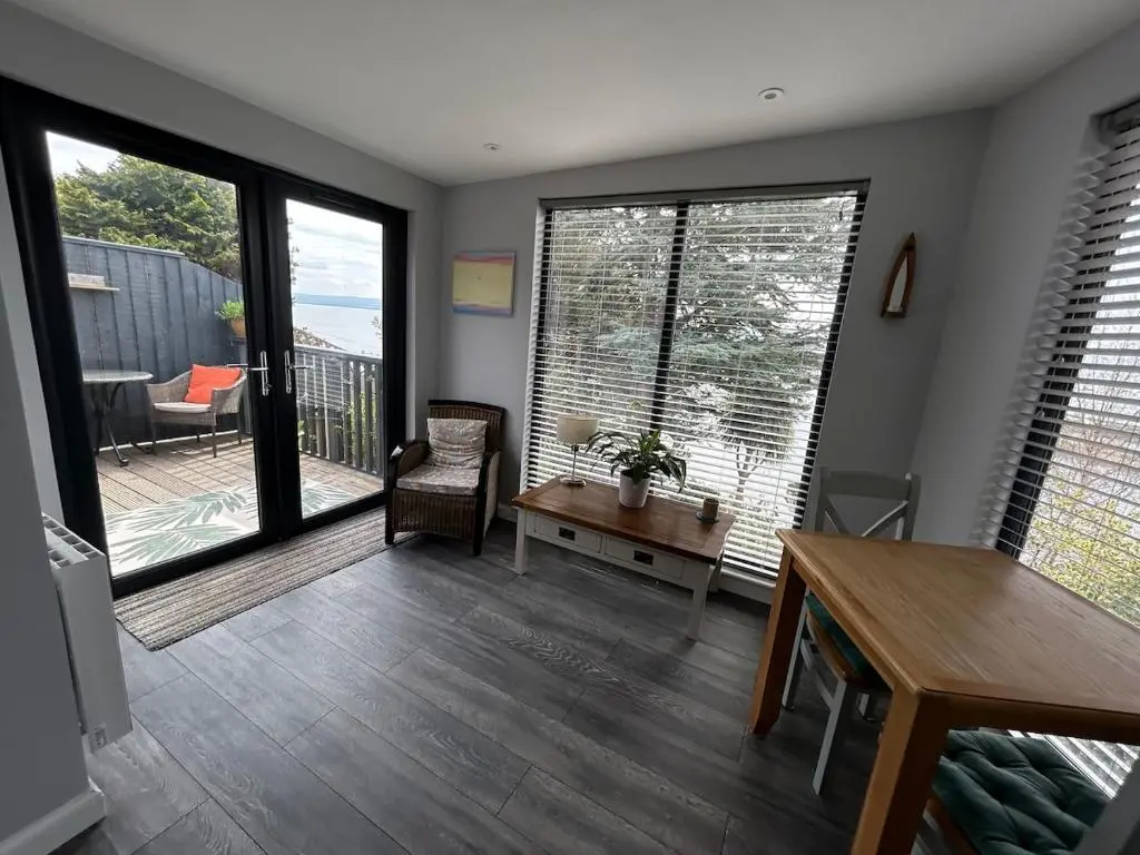 a living room with large windows and a wooden table at Cosy coastal hideaway with incredible sea views in Fortrose
