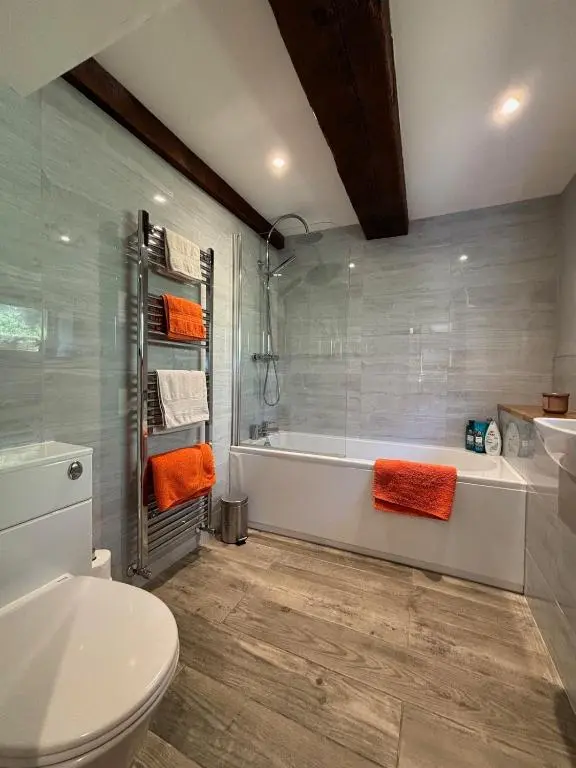 a bathroom with a tub and a toilet with orange towels at Cosy coastal hideaway with incredible sea views in Fortrose