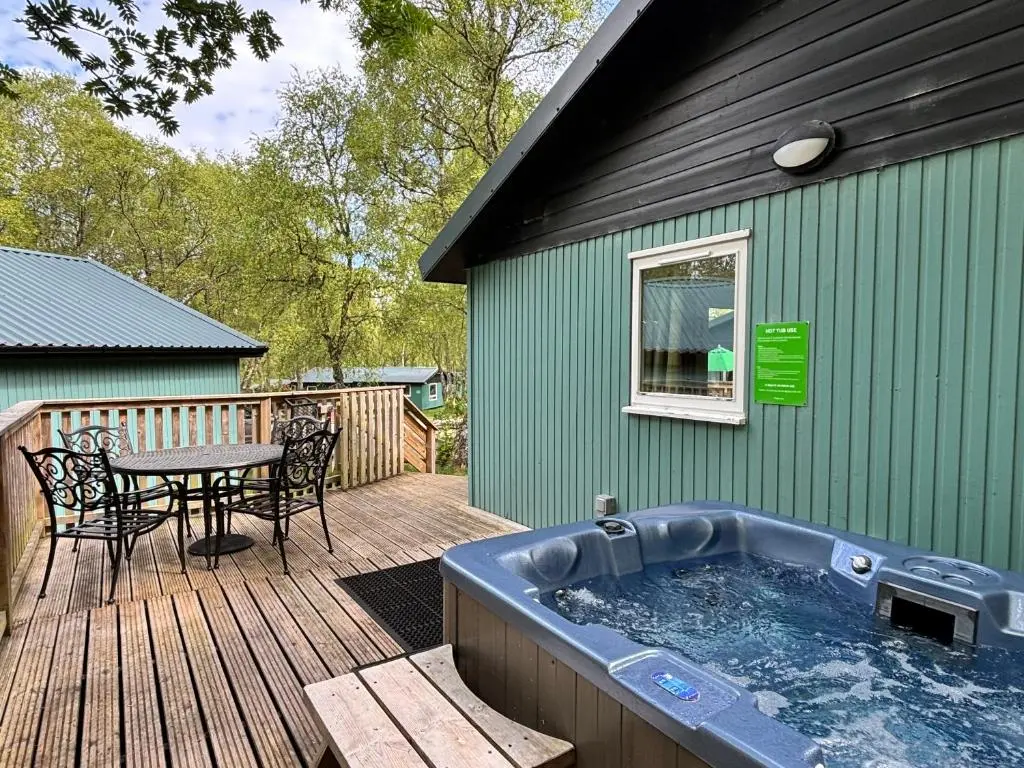 a hot tub on a deck with a table at Bracken Lodge 8 with Hot Tub in Belladrum
