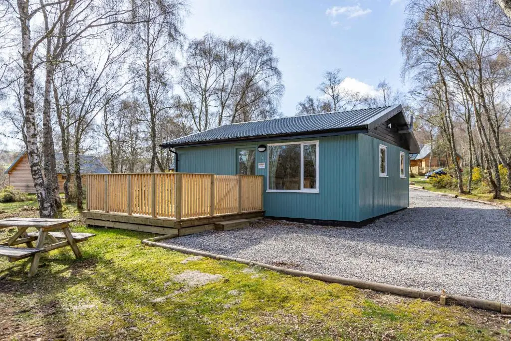 a small green tiny house with a picnic table at Bracken Lodge 16 with Hot Tub in Belladrum