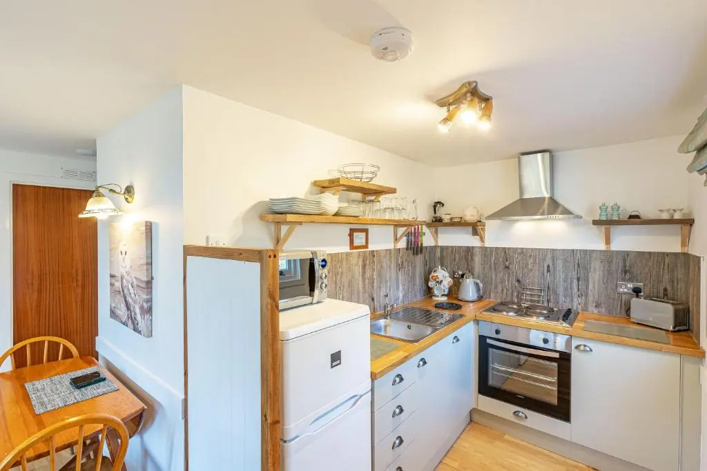 a kitchen with white appliances and a wooden table at Bracken Lodge 16 with Hot Tub in Belladrum