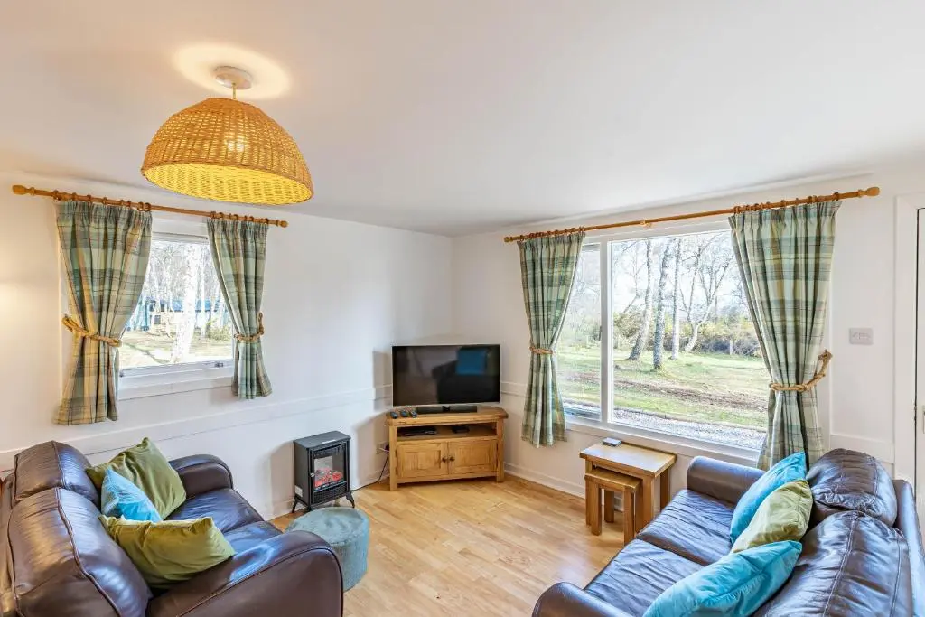 a living room with a couch and a tv at Bracken Lodge 16 with Hot Tub in Belladrum