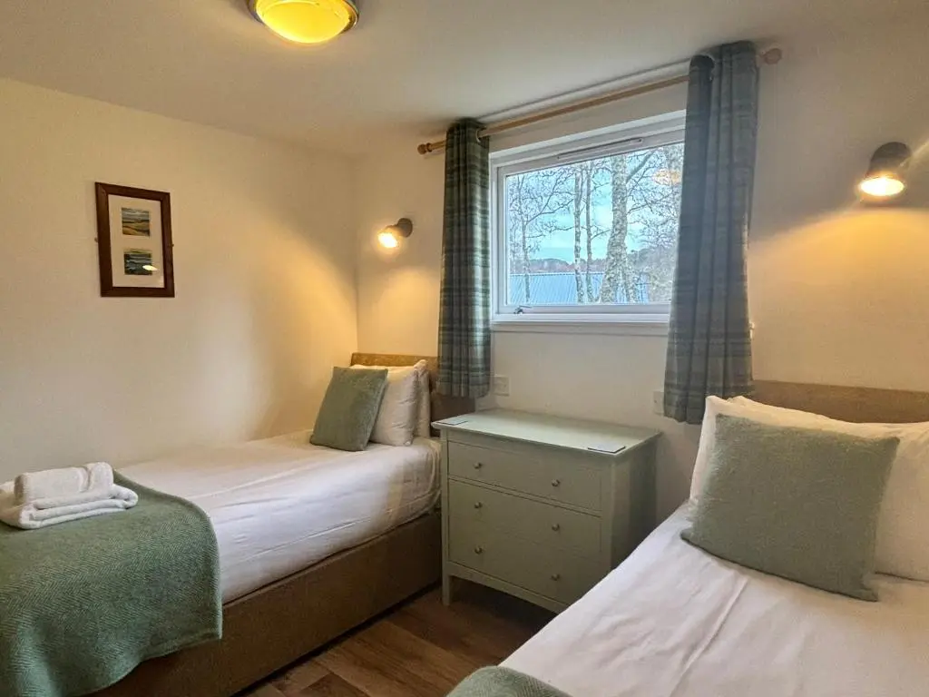 a small bedroom with two beds and a window at Bracken Lodge 16 with Hot Tub in Belladrum