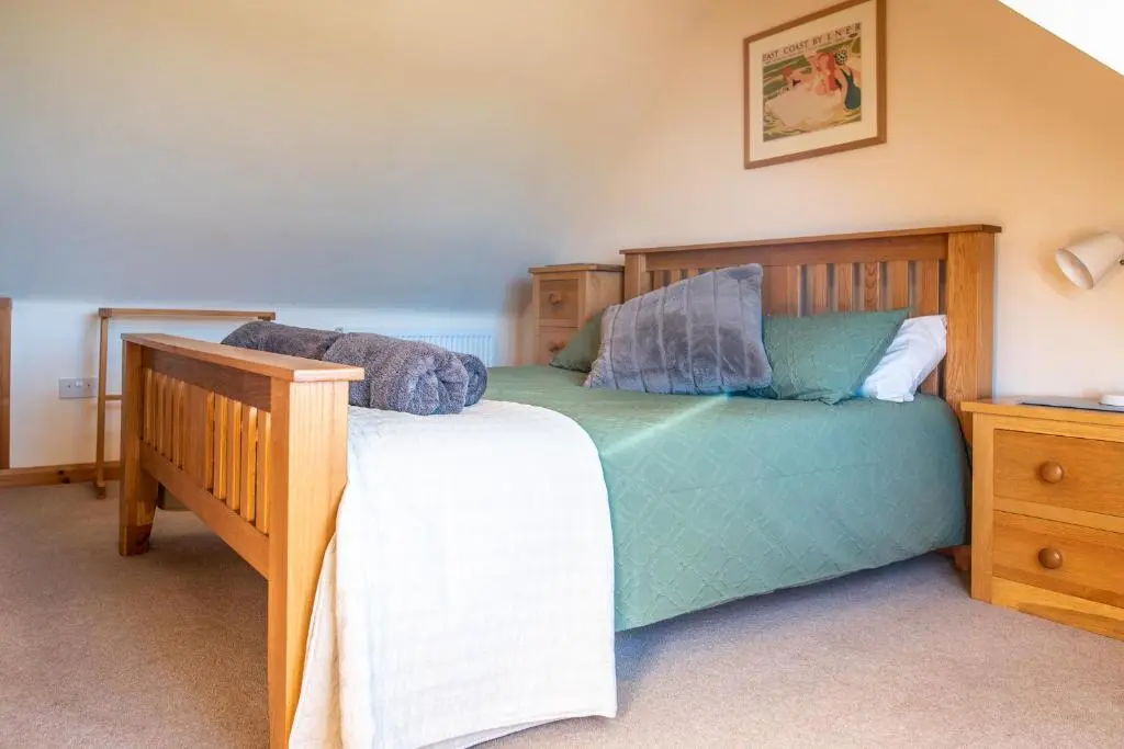 a bedroom with a wooden bed and a wooden dresser at Hillside Cottage in Aberdeen