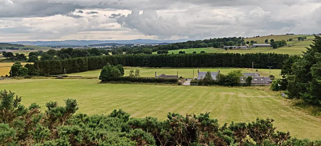 a large field of grass with houses in the distance at Hillside Cottage in Aberdeen