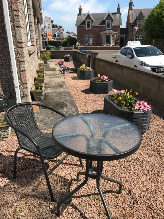 a table and a chair sitting on a gravel patio at Haste Ye Back in Inverness