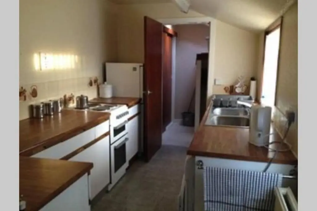 a kitchen with a sink and a refrigerator at Preston Villa, spacious ground floor apartment in Buckie
