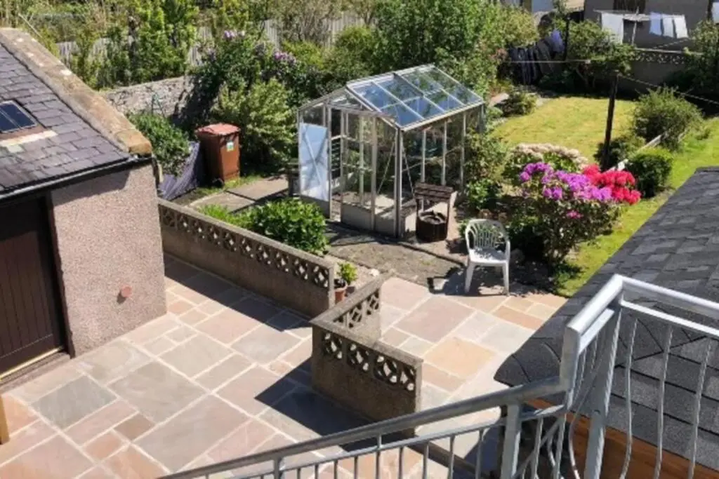 a garden with a greenhouse on a patio at Preston Villa, spacious ground floor apartment in Buckie