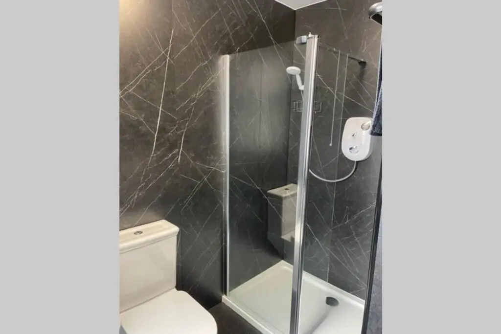 a bathroom with a toilet and a glass shower at Preston Villa, spacious ground floor apartment in Buckie