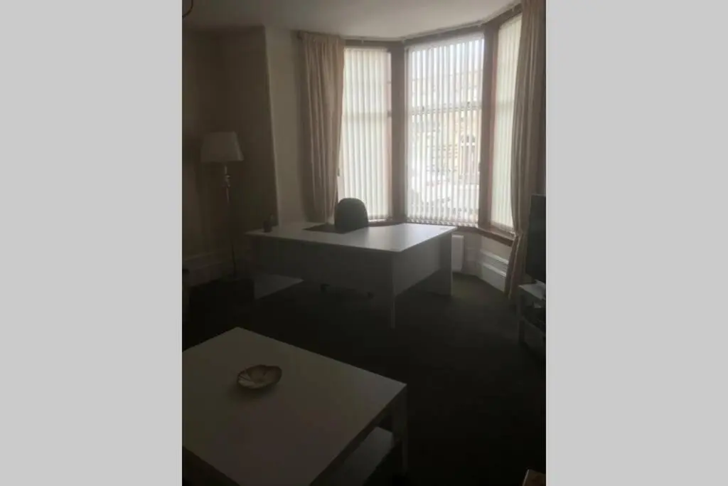a living room with a table and windows at Preston Villa, spacious ground floor apartment in Buckie