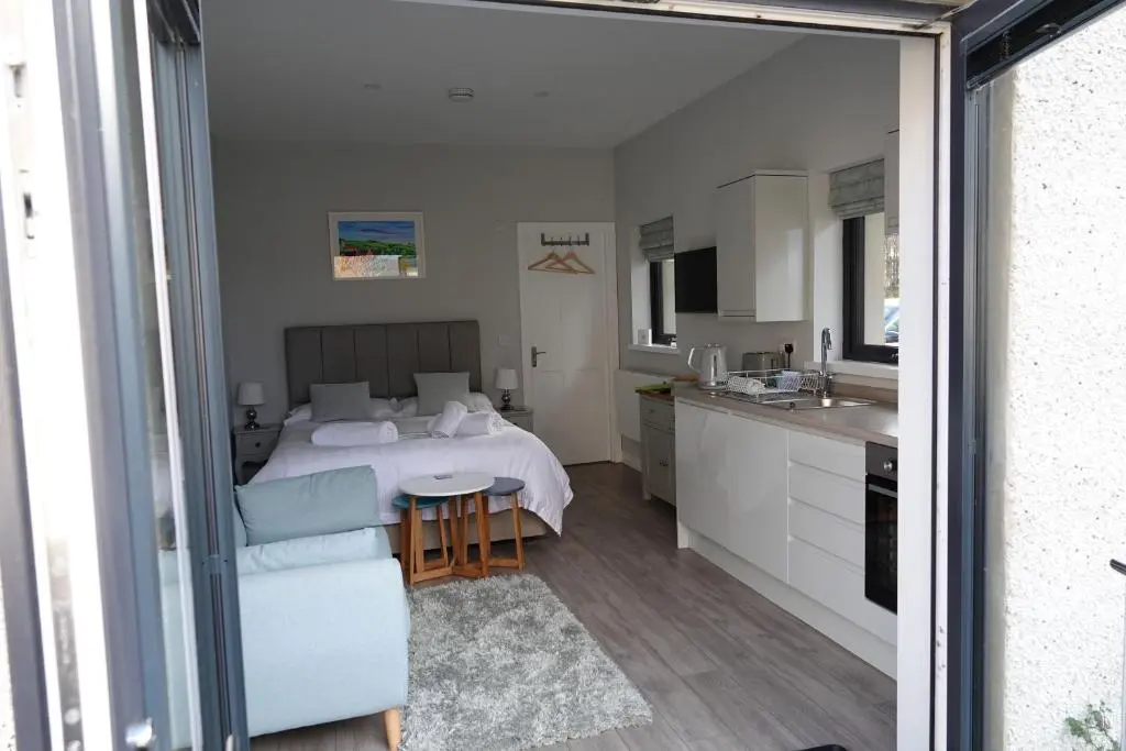 a bedroom with a bed and a table and a kitchen at Fyrish View in Dingwall
