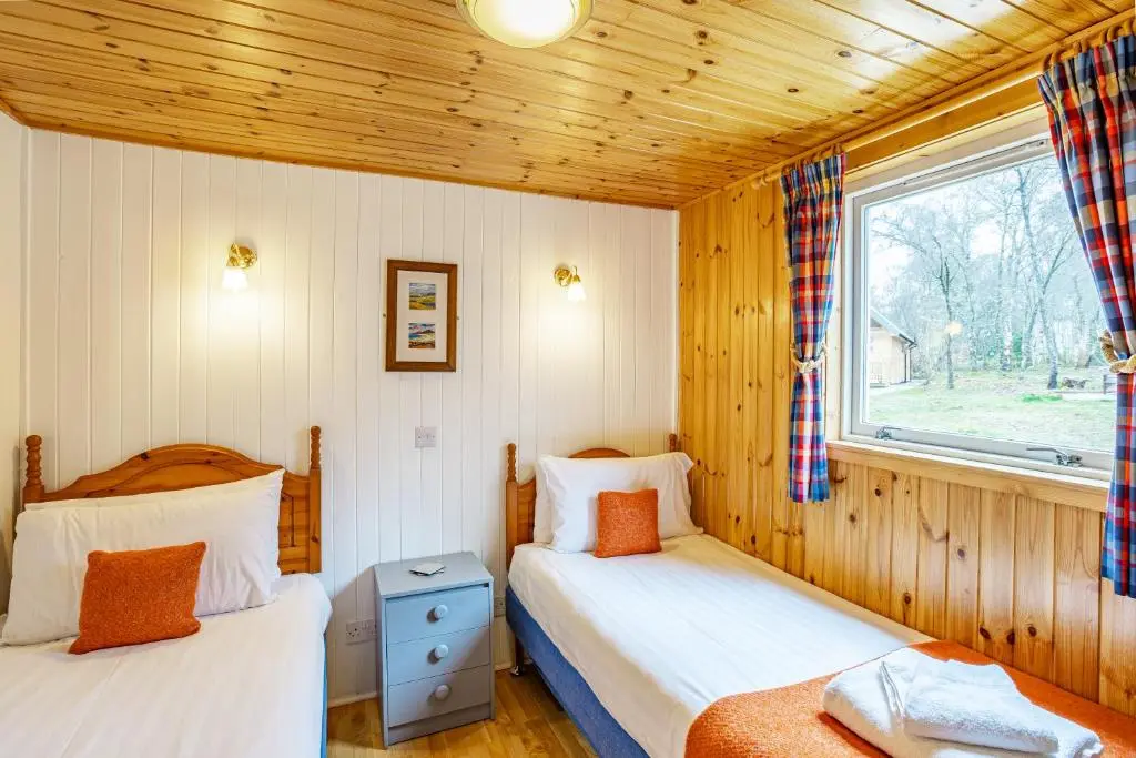 a bedroom with two beds and a window at Heather Lodge 4, sleeping 6 in Belladrum