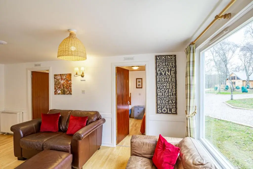 a living room with a couch and a window at Heather Lodge 4, sleeping 6 in Belladrum