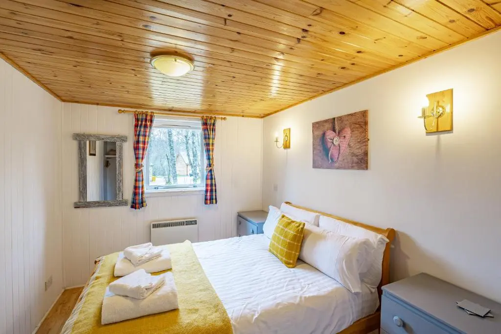 a bedroom with a bed and a wooden ceiling at Heather Lodge 4, sleeping 6 in Belladrum