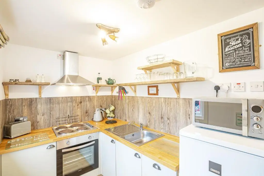 a kitchen with white cabinets and a sink at Heather Lodge 4, sleeping 6 in Belladrum
