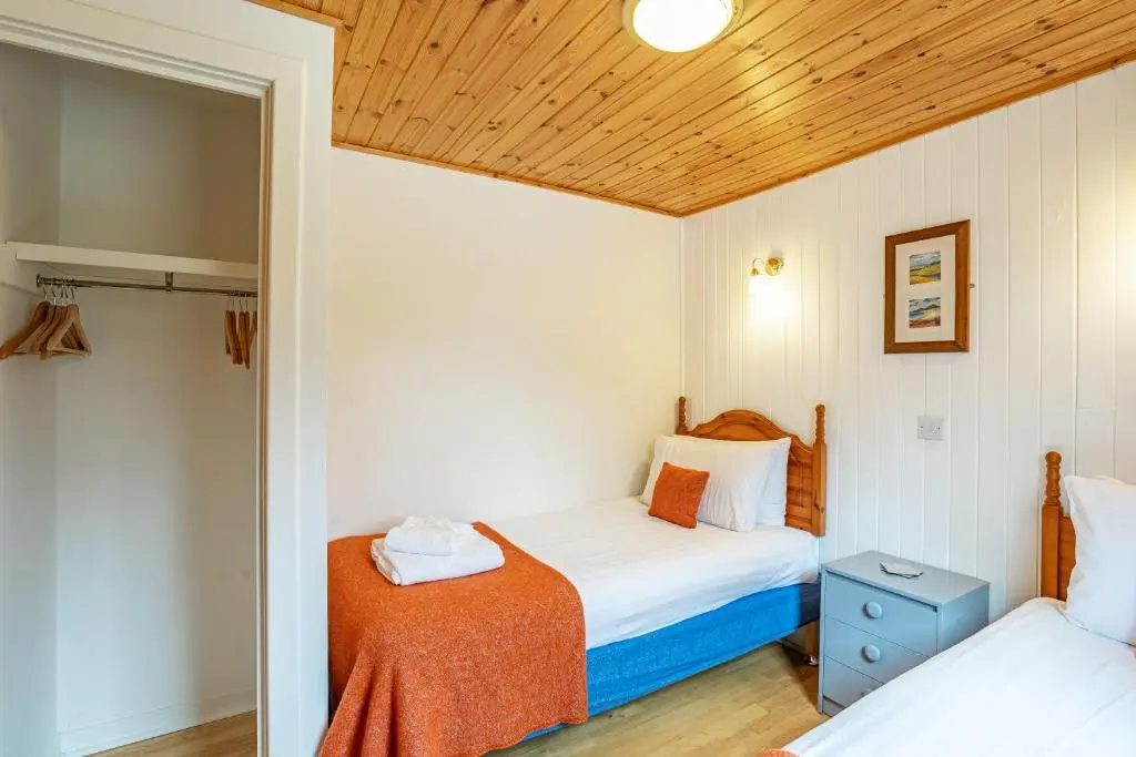 a bedroom with two beds and a wooden ceiling at Heather Lodge 4, sleeping 6 in Belladrum