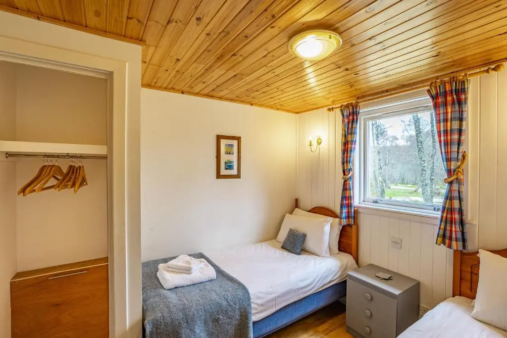 a bedroom with two beds and a window at Heather Lodge 4, sleeping 6 in Belladrum
