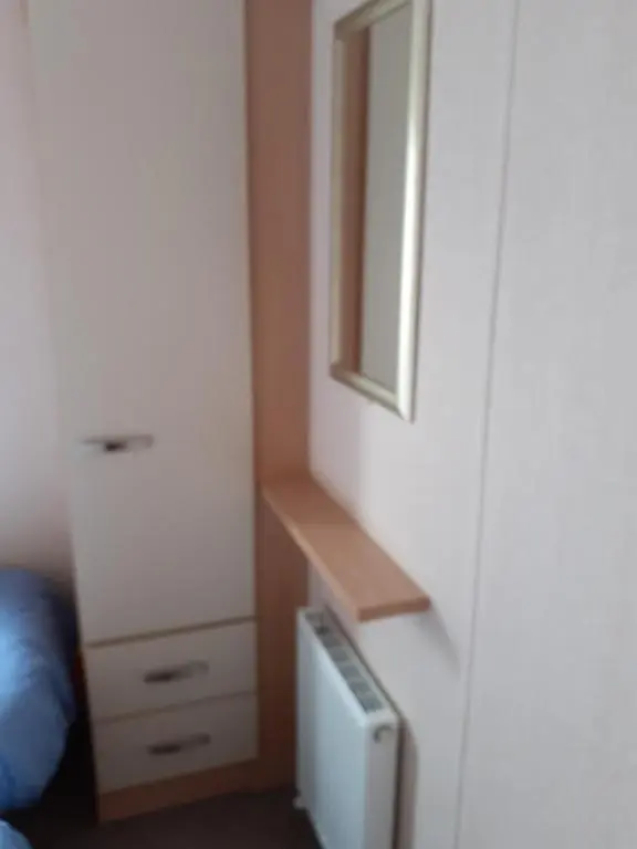 a small bedroom with a dresser and a mirror at RICK'S RETREAT static caravan near the beach with free wifi in Lossiemouth