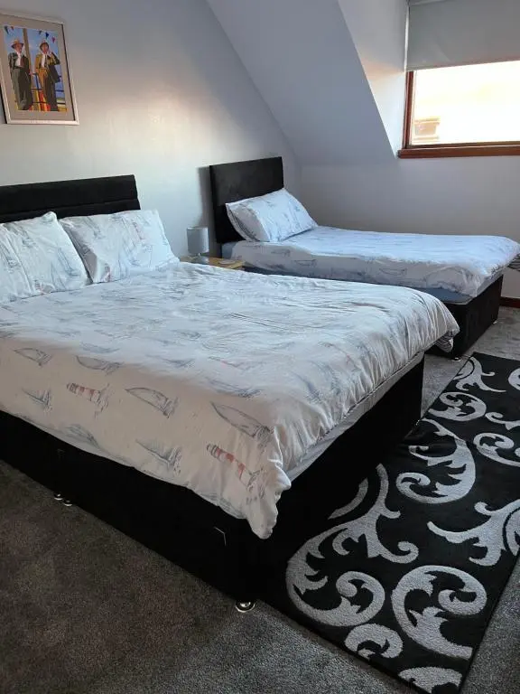two twin beds in a bedroom with a rug at No 22 in Banff