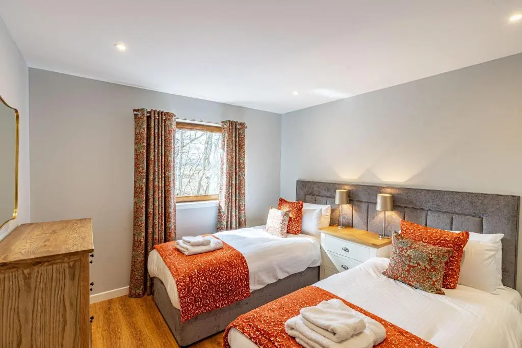 a bedroom with two beds and a window at Monarch Lodge 14 with Hot Tub in Belladrum