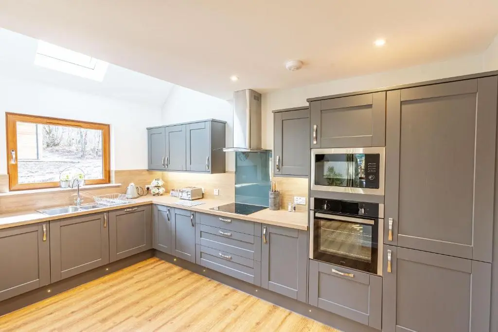 a large kitchen with gray cabinets and a window at Monarch Lodge 14 with Hot Tub in Belladrum