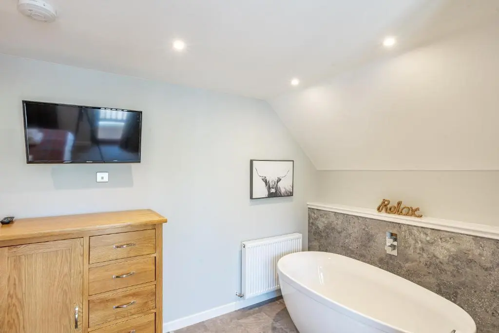 a bathroom with a tub and a tv on the wall at Monarch Lodge 14 with Hot Tub in Belladrum