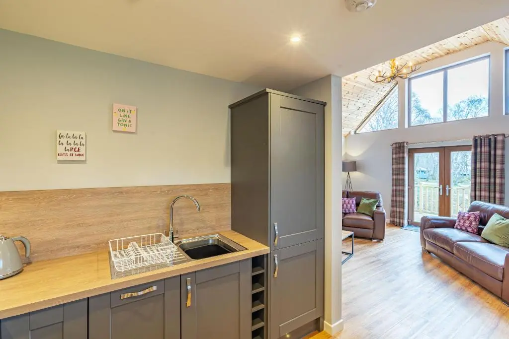 a kitchen with a sink and a living room at Thistle Lodge 20 with Hot Tub in Belladrum
