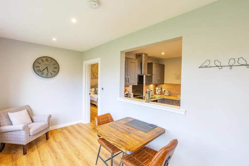 a dining room with a table and a clock on the wall at Thistle Lodge 20 with Hot Tub in Belladrum