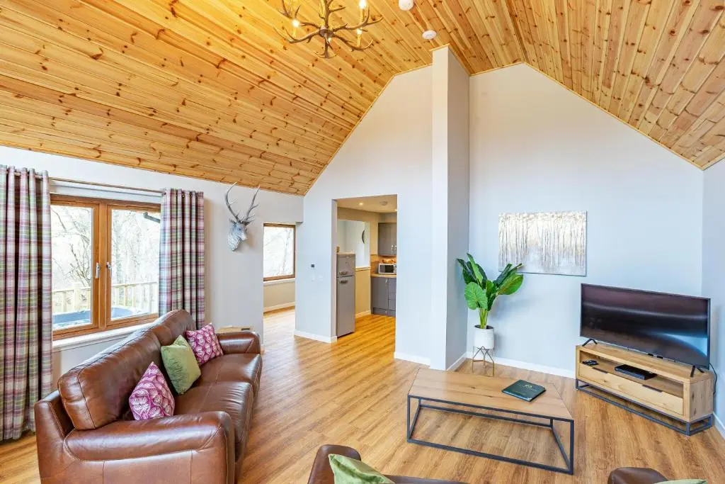 a living room with a couch and a tv at Thistle Lodge 20 with Hot Tub in Belladrum