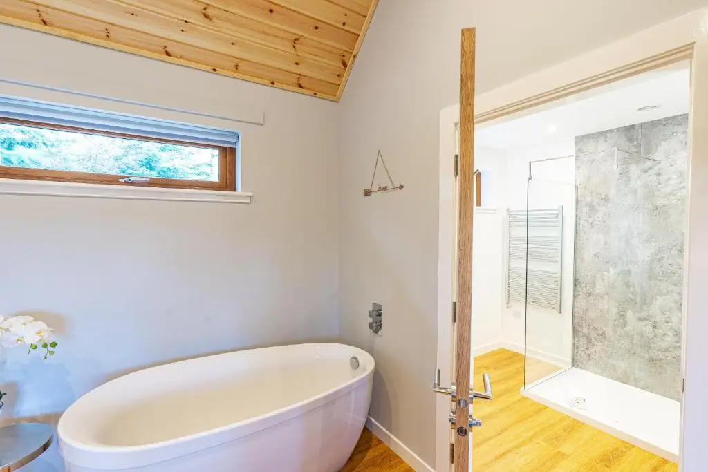 a white bath tub in a bathroom with a window at Thistle Lodge 20 with Hot Tub in Belladrum