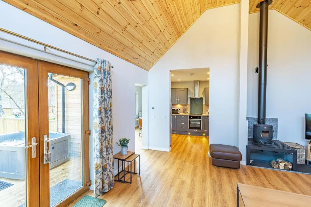 an open kitchen and living room with a wood ceiling at Thistle Lodge 22 with Hot Tub in Belladrum