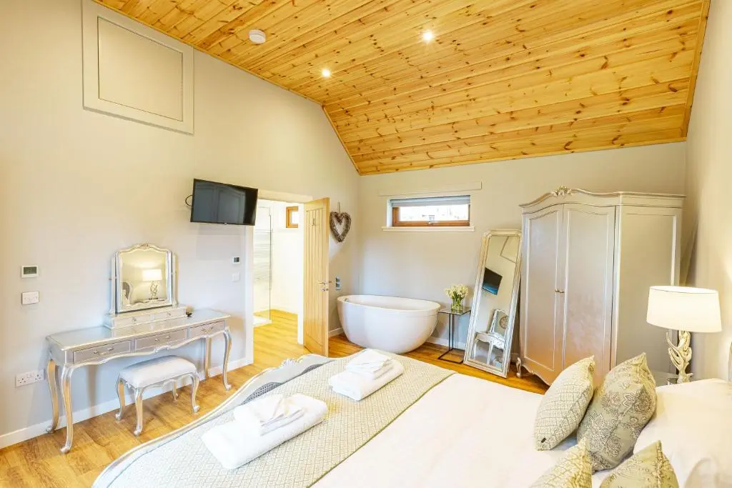 a bedroom with a large bed and a bathroom at Thistle Lodge 18 with Hot Tub in Belladrum