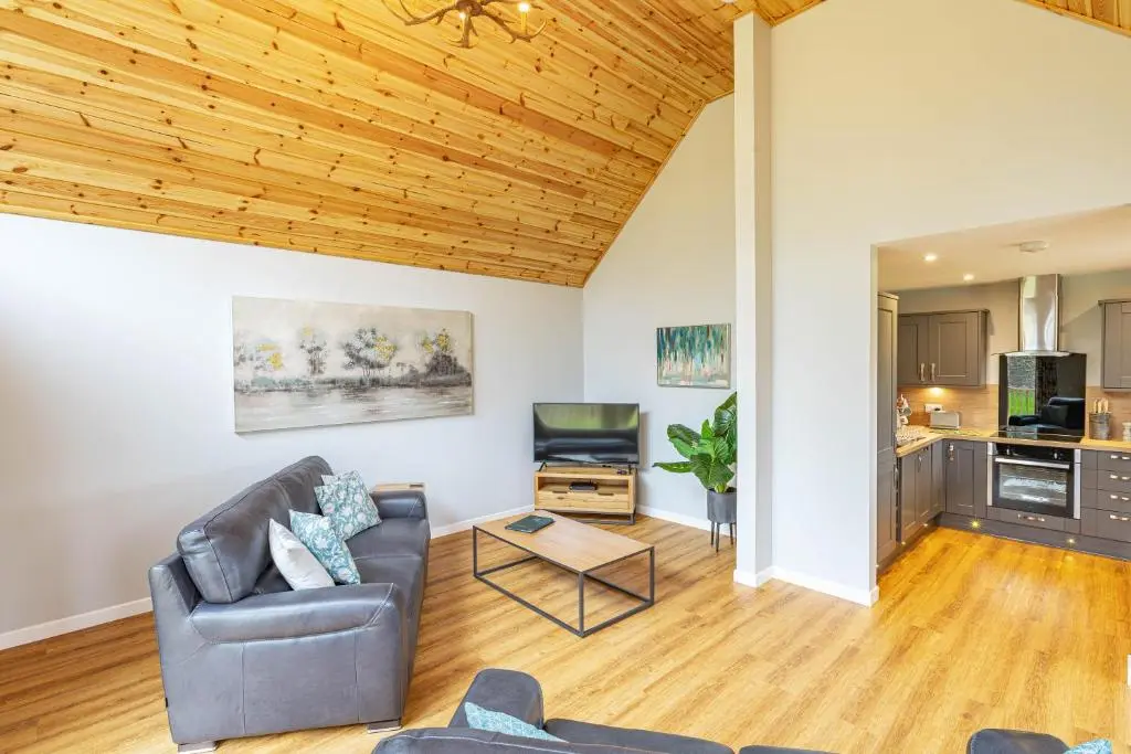a living room with a couch and a table at Thistle Lodge 18 with Hot Tub in Belladrum