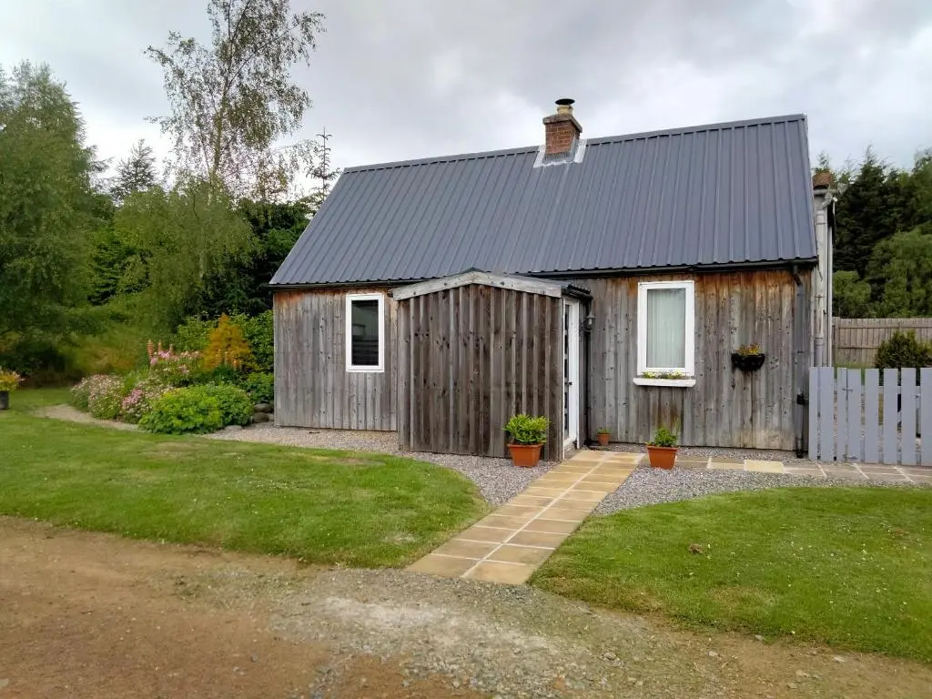 a small wooden house with a grass yard at Small cosy bothy in Dingwall