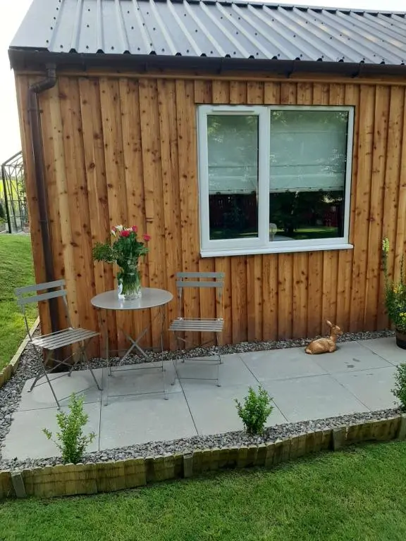 a patio with a table and chairs and a window at Beautiful studio chalet in the Highlands in Inverness