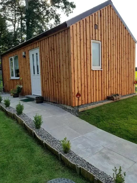 a small wooden building with a door and a sidewalk at Beautiful studio chalet in the Highlands in Inverness