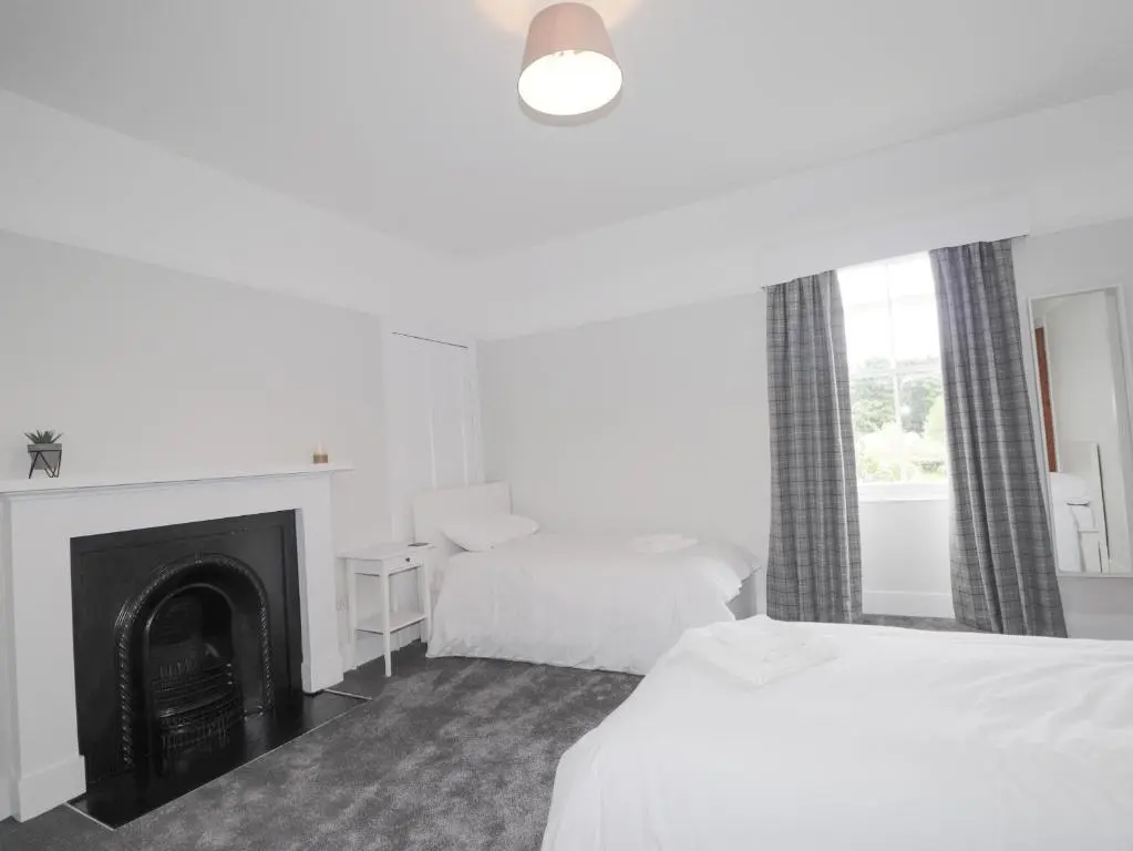 a hotel room with two beds and a fireplace at Garden House - Brodie Castle in Forres