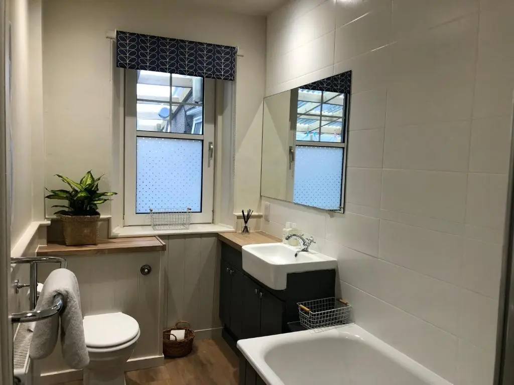a bathroom with a sink and a toilet and a tub at Nurse's Cottage in Tomintoul