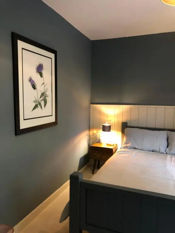 a bedroom with a bed and a picture on the wall at Nurse's Cottage in Tomintoul
