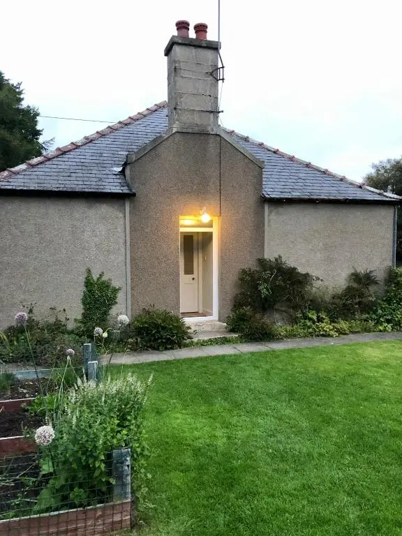 a house with a green yard with a lawn at Nurse's Cottage in Tomintoul