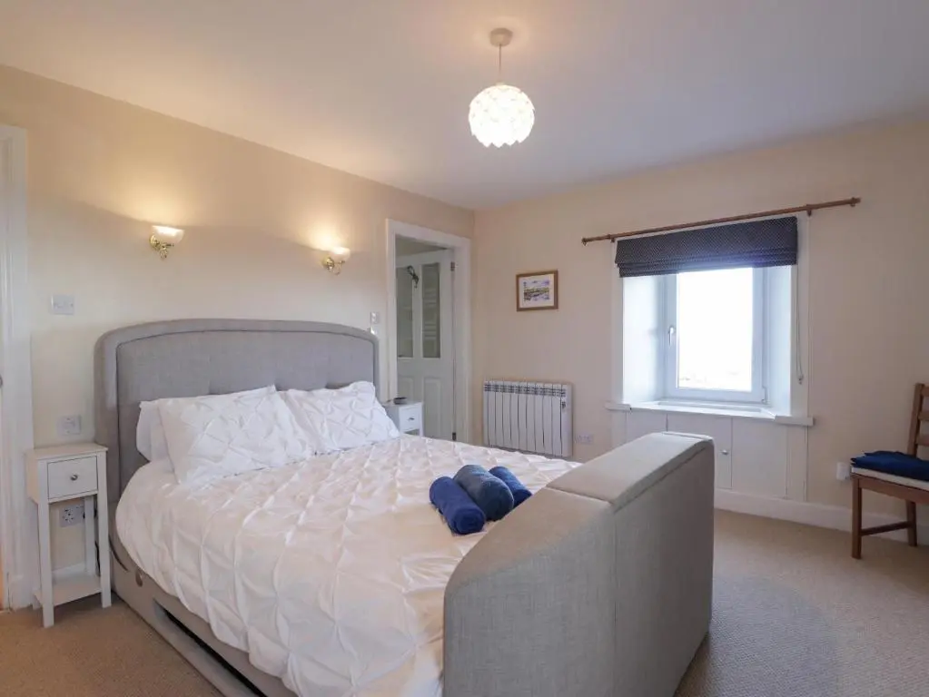 a bedroom with a large white bed with a window at Seaview at The Doocot in Elgin
