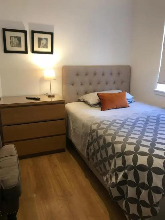 a bedroom with a bed and a dresser with a lamp at Town centre 4xbed 4xbath apartment in Elgin