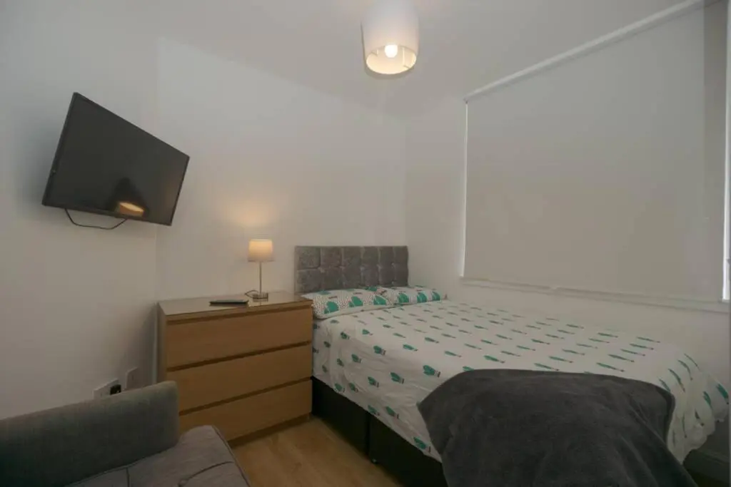 a bedroom with a bed and a dresser with a tv at Town centre 4xbed 4xbath apartment in Elgin